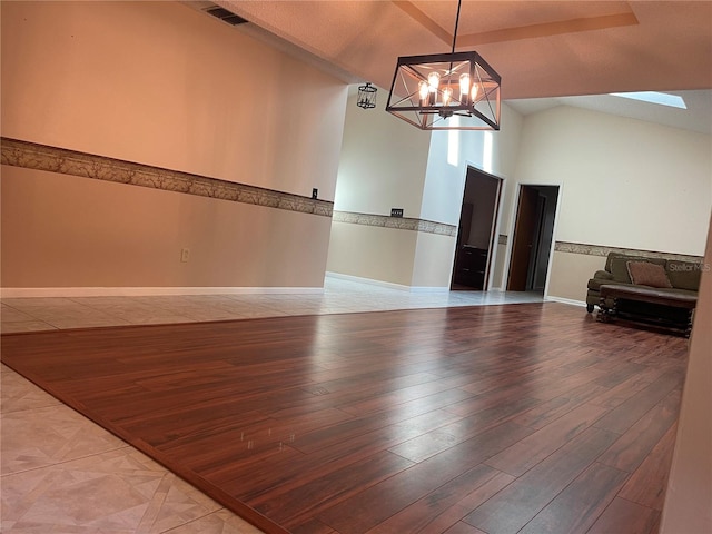 empty room featuring an inviting chandelier, wood-type flooring, and high vaulted ceiling