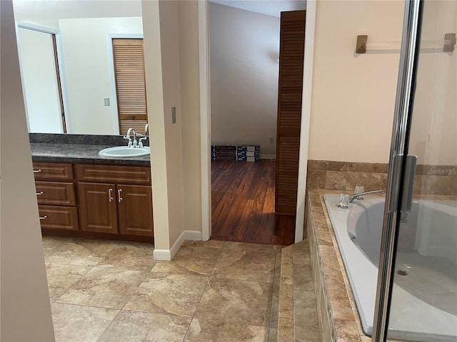 bathroom featuring vanity and a relaxing tiled tub