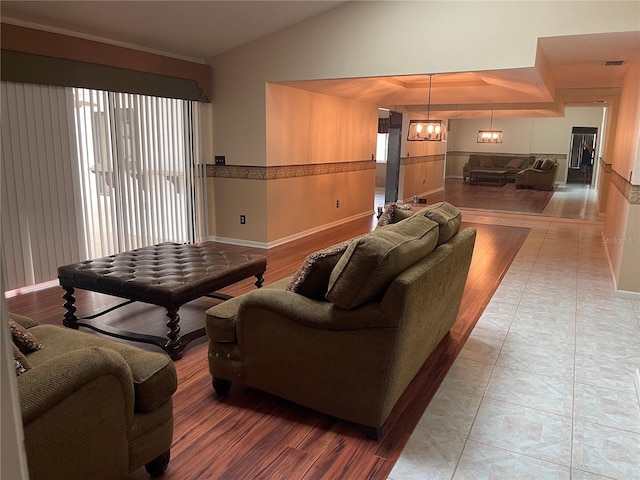 living room with a notable chandelier, vaulted ceiling, and hardwood / wood-style floors