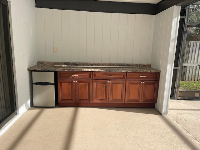 bar with stainless steel refrigerator and dark stone counters