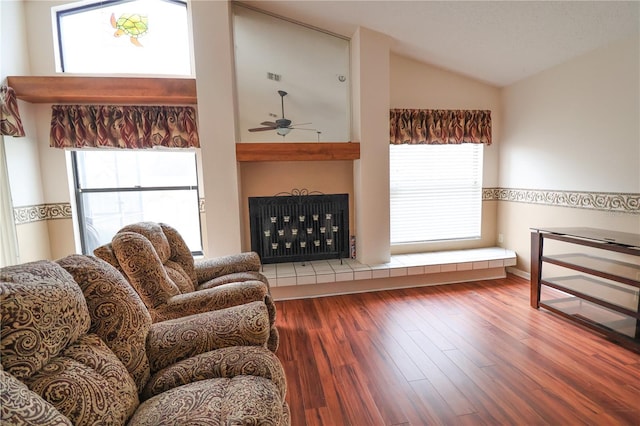 living room featuring hardwood / wood-style flooring, a tile fireplace, lofted ceiling, and ceiling fan