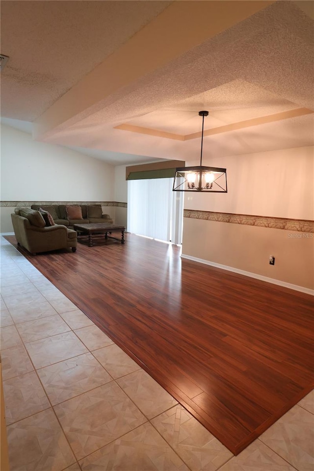 unfurnished dining area featuring an inviting chandelier, a textured ceiling, and light hardwood / wood-style flooring