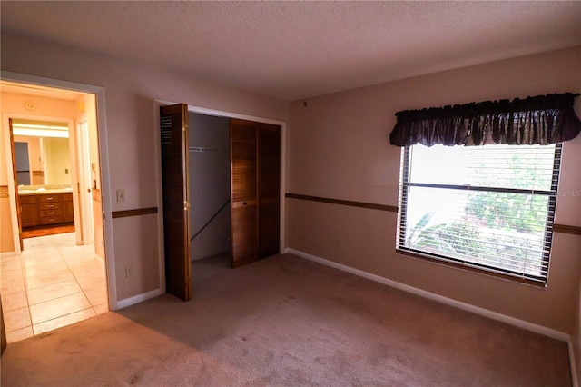 unfurnished bedroom featuring light colored carpet, a closet, and a textured ceiling