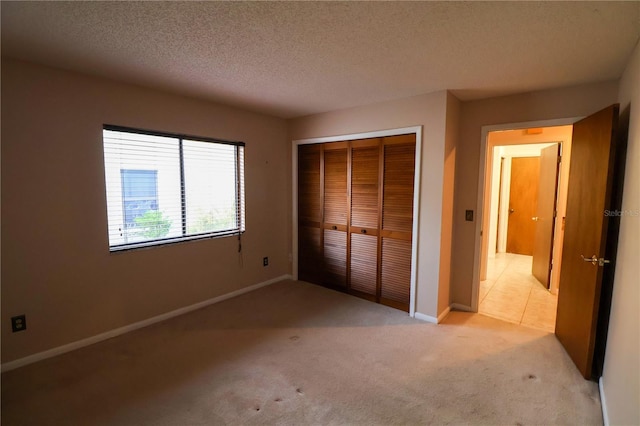 unfurnished bedroom with light carpet, a textured ceiling, and a closet