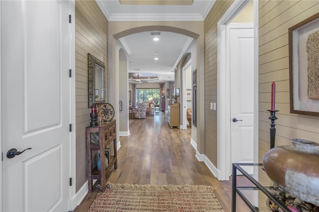 hall featuring hardwood / wood-style floors, crown molding, and wood walls