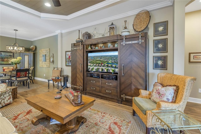 living room featuring a tray ceiling, an inviting chandelier, crown molding, and light hardwood / wood-style flooring