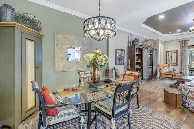 dining room featuring hardwood / wood-style floors, a notable chandelier, a raised ceiling, and ornamental molding