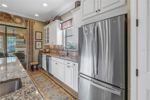 kitchen with light stone counters, white cabinets, light hardwood / wood-style floors, and appliances with stainless steel finishes