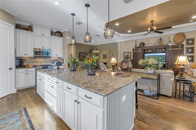 kitchen featuring white cabinetry, a kitchen island with sink, ceiling fan, and light hardwood / wood-style floors