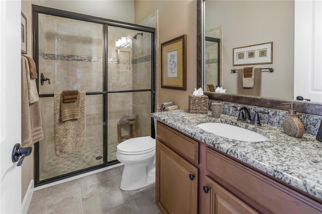 bathroom featuring tile patterned flooring, vanity, toilet, and a shower with shower door