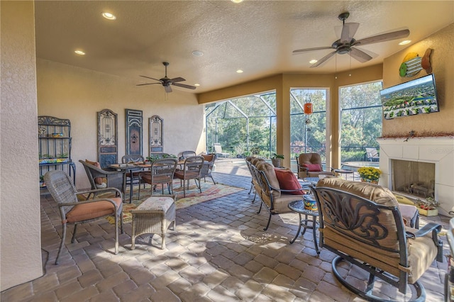 view of patio featuring a tile fireplace, ceiling fan, and a lanai