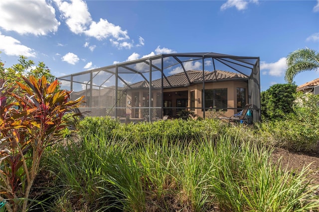 rear view of property featuring glass enclosure