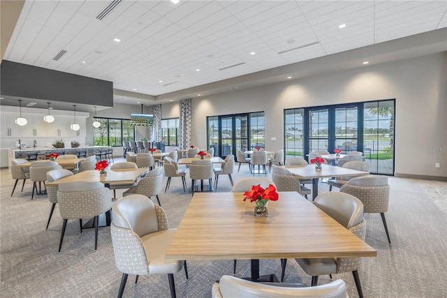 dining space featuring a towering ceiling, light colored carpet, and a wealth of natural light