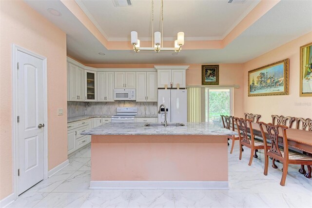 397 Doniphan Dr, Port Charlotte, FL 33954 - kitchen with white appliances, a tray ceiling, a center island with sink, light stone countertops, and crown molding