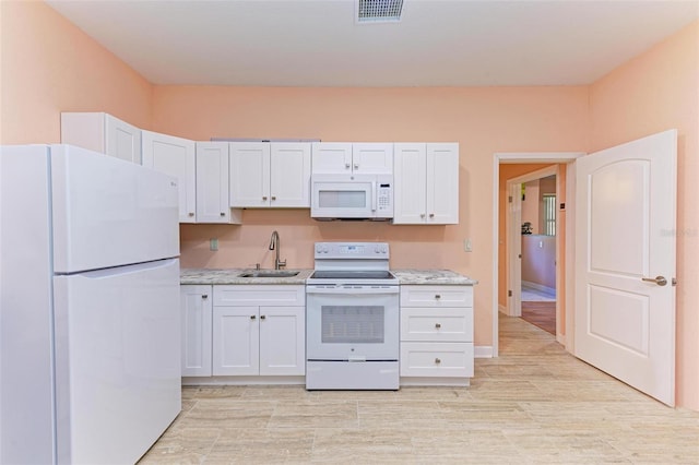 kitchen featuring white cabinetry, sink, light stone countertops, and white appliances