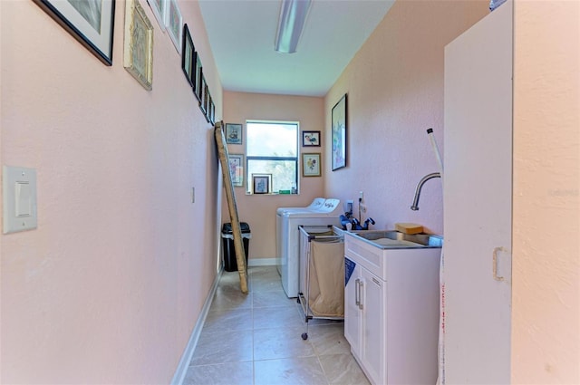 clothes washing area featuring light tile patterned flooring, cabinets, separate washer and dryer, and sink