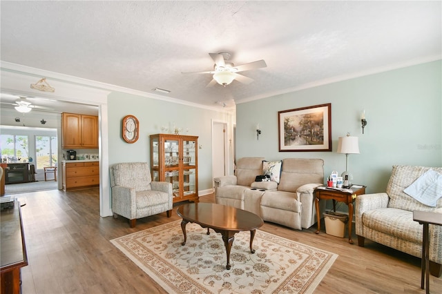 living room featuring a textured ceiling, ceiling fan, crown molding, and light hardwood / wood-style flooring