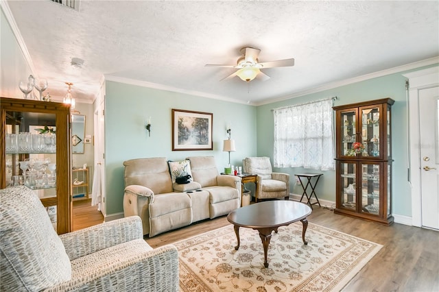 living room with hardwood / wood-style floors, a textured ceiling, ceiling fan, and ornamental molding