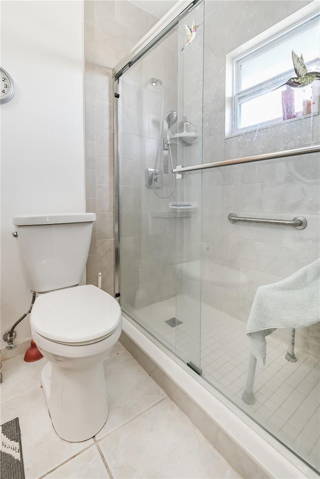 bathroom featuring tile patterned flooring, toilet, and an enclosed shower