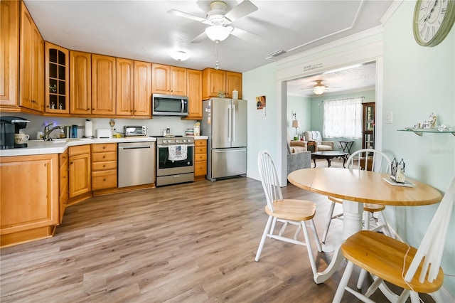 kitchen with ceiling fan, sink, stainless steel appliances, and light hardwood / wood-style flooring