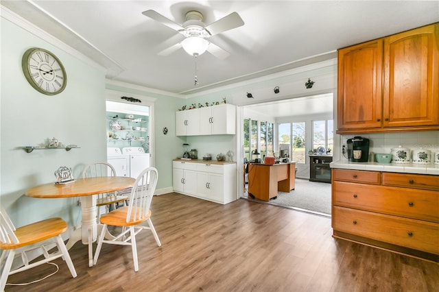 kitchen featuring ceiling fan, tasteful backsplash, separate washer and dryer, crown molding, and light hardwood / wood-style floors