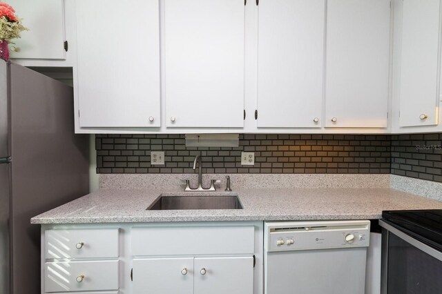 kitchen with dishwasher, decorative backsplash, white cabinetry, and sink