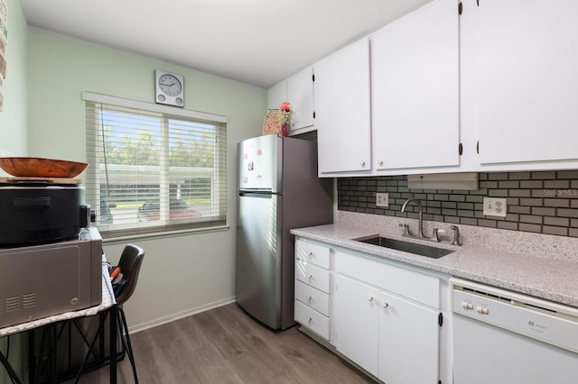 kitchen featuring hardwood / wood-style floors, backsplash, white dishwasher, sink, and white cabinetry