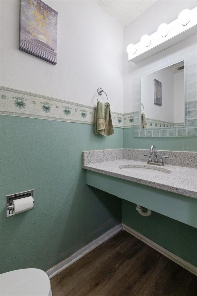 bathroom featuring hardwood / wood-style floors, a textured ceiling, toilet, and sink