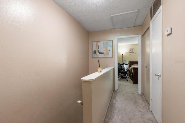 hall featuring light colored carpet and a textured ceiling