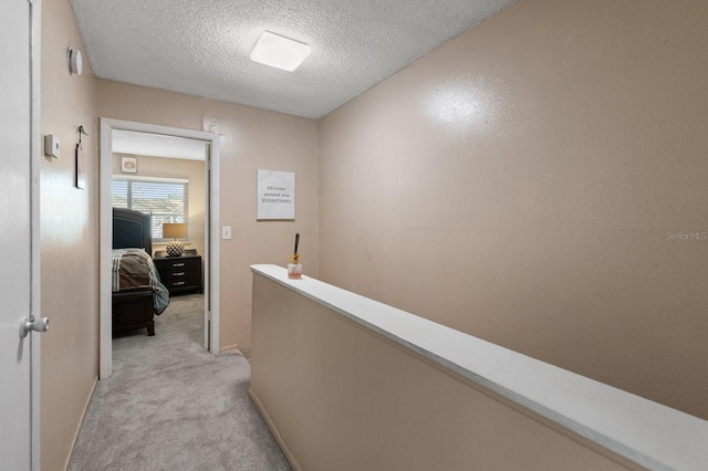 hall featuring a textured ceiling and light carpet