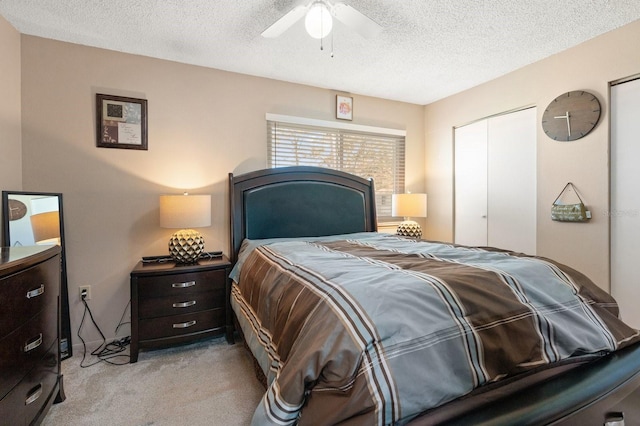 bedroom featuring ceiling fan, light colored carpet, a textured ceiling, and a closet