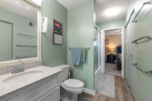 bathroom featuring vanity, wood-type flooring, a textured ceiling, and toilet