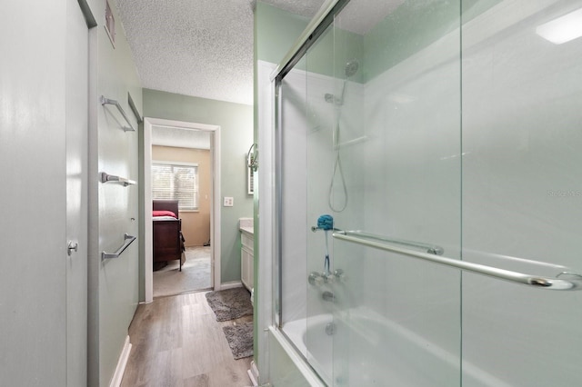 bathroom with enclosed tub / shower combo, vanity, wood-type flooring, and a textured ceiling