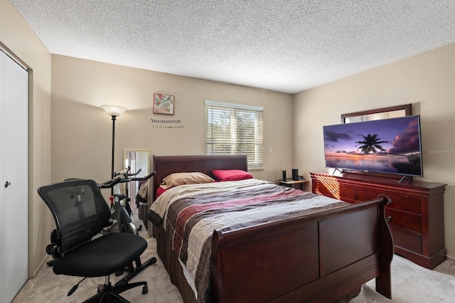 bedroom featuring light carpet, a textured ceiling, and a closet