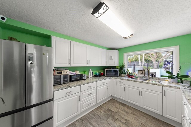 kitchen featuring light wood-type flooring, white cabinetry, sink, and appliances with stainless steel finishes