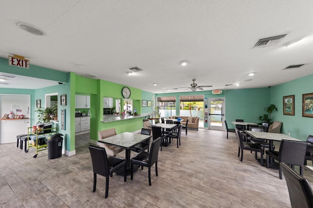 dining space with a textured ceiling, light hardwood / wood-style floors, and ceiling fan