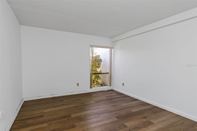 spare room featuring dark wood-type flooring and a textured ceiling