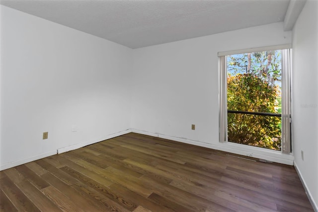 spare room with dark hardwood / wood-style floors and a textured ceiling