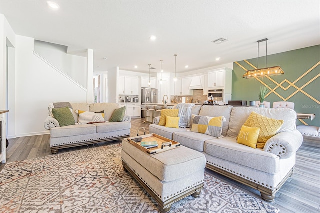 living room with sink, an inviting chandelier, and hardwood / wood-style flooring