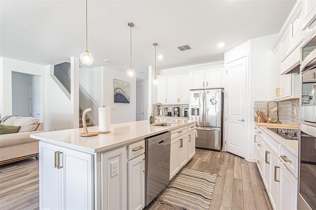 kitchen featuring decorative backsplash, appliances with stainless steel finishes, a kitchen island with sink, sink, and decorative light fixtures