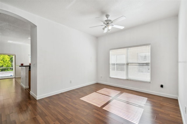 empty room with a textured ceiling, dark hardwood / wood-style flooring, and ceiling fan