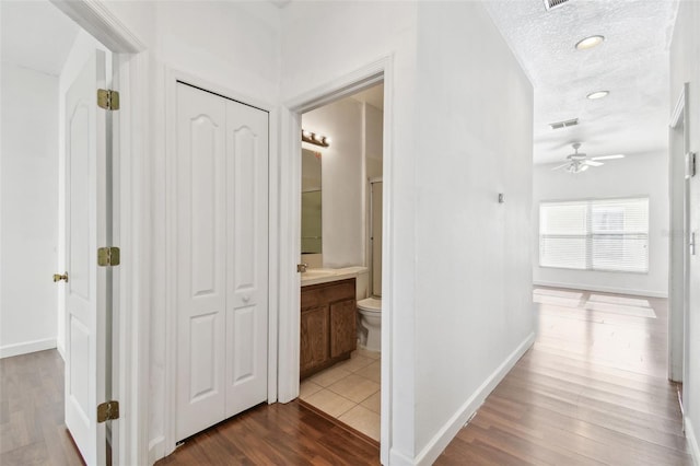 corridor with a textured ceiling and hardwood / wood-style flooring