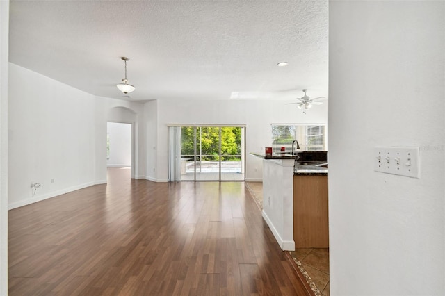 unfurnished living room with a textured ceiling, dark hardwood / wood-style floors, ceiling fan, and sink