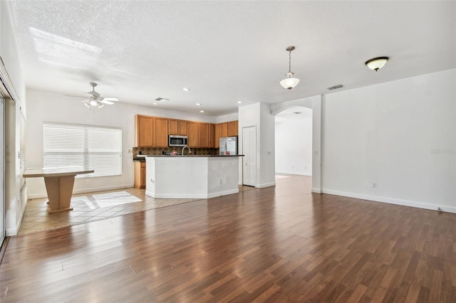 unfurnished living room featuring hardwood / wood-style flooring, ceiling fan, and a textured ceiling