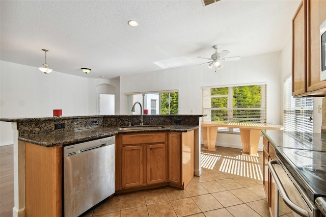 kitchen featuring ceiling fan, dark stone countertops, sink, and stainless steel appliances