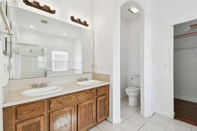 bathroom featuring tile patterned flooring, vanity, toilet, and walk in shower