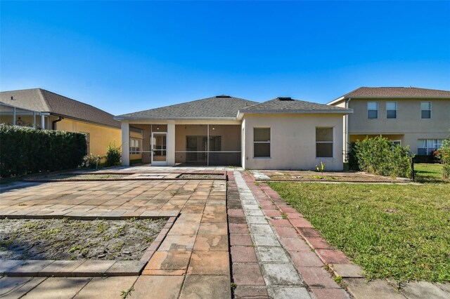 rear view of property with a sunroom, a yard, and a patio