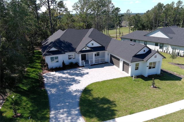 view of front of house with driveway, a shingled roof, and a front lawn