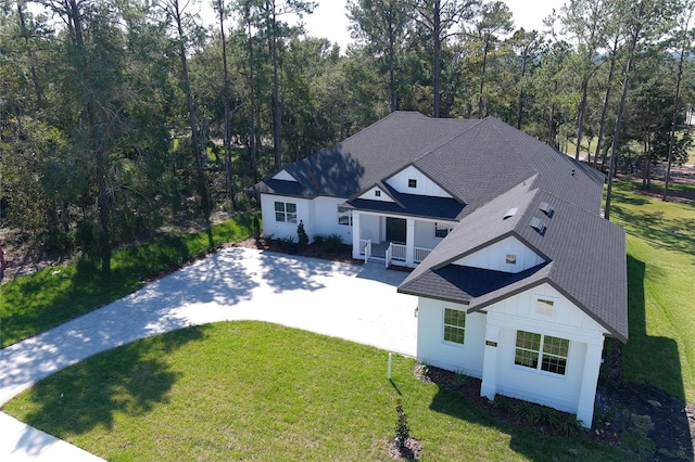 view of front of house with driveway, a shingled roof, board and batten siding, and a front yard