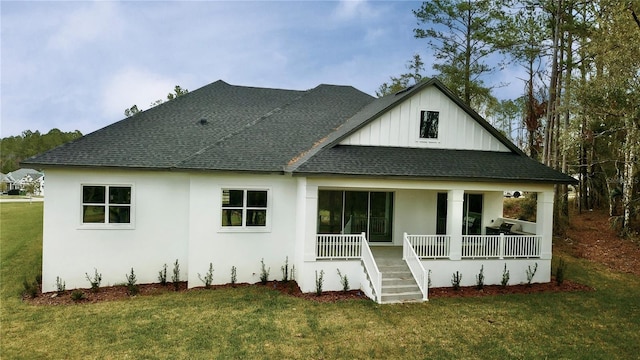 rear view of house featuring covered porch, roof with shingles, and a lawn